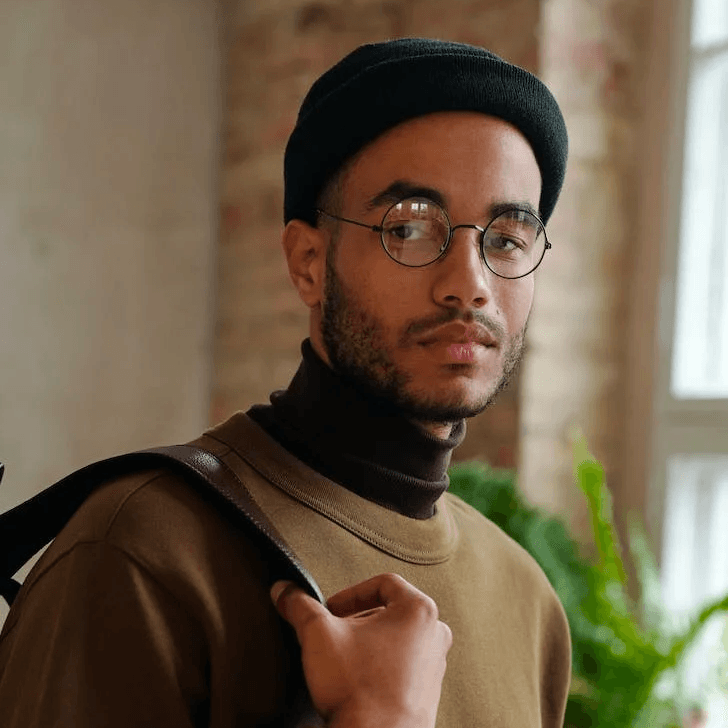 Ein Mann mit Brille in einem Büro mit einer Pflanze dahinter.