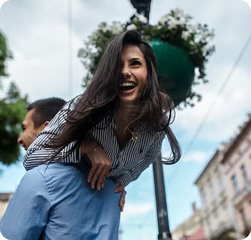 Eine lächelnde, glückliche Frau auf den Schultern eines Mannes, was emotionale Erleichterung darstellt.