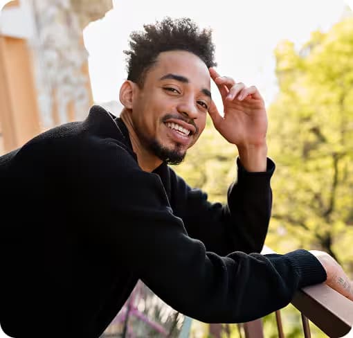 Lächelnder Mann auf Balkon, deutet auf Stressreduktion durch Cannabis.