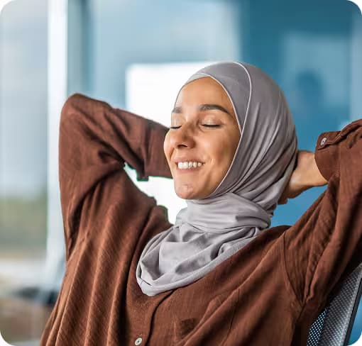 Lächelnde Frau mit Kopftuch lehnt entspannt zurück – Symptombehandlung durch Cannabis.
